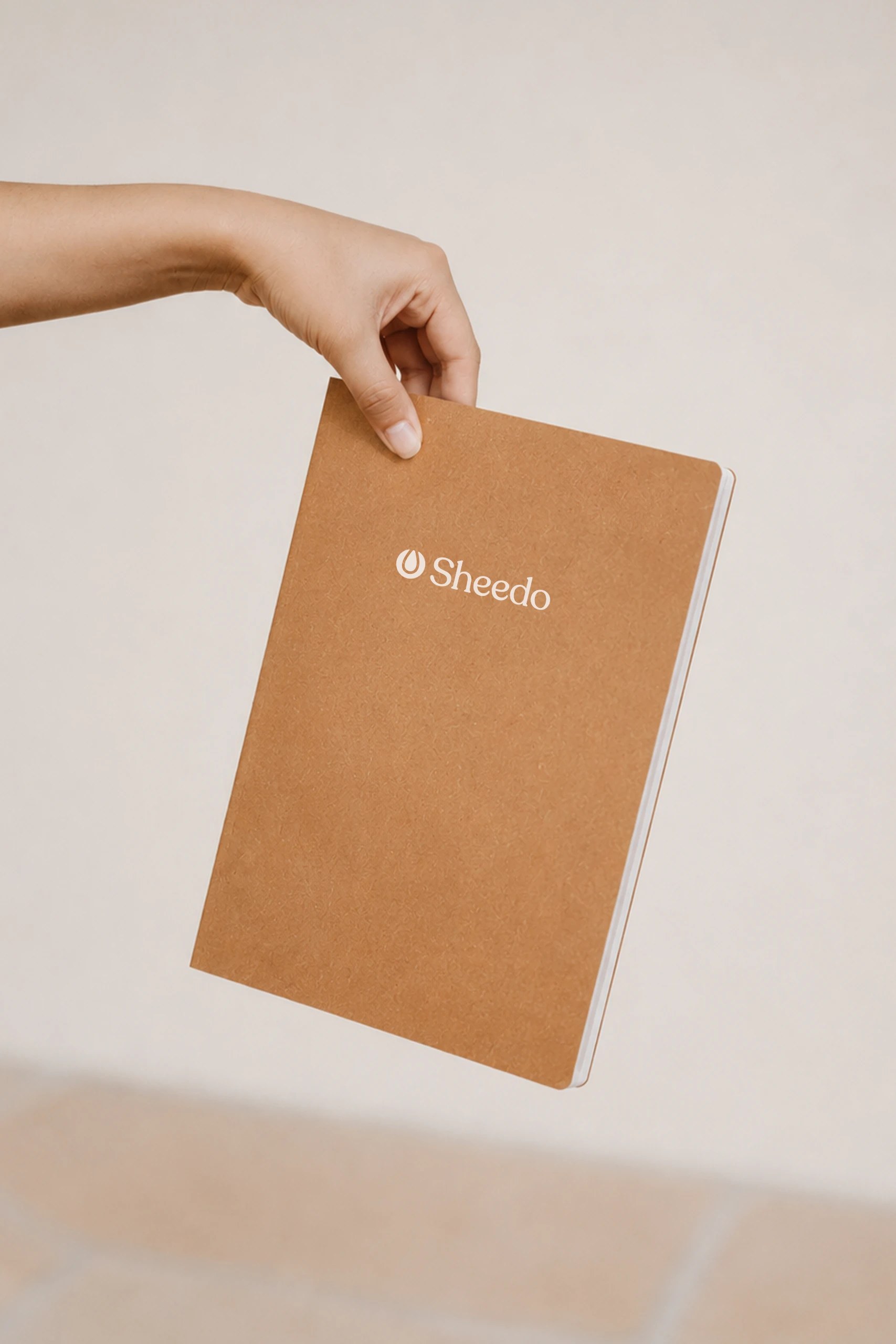 Cuaderno de cuero marrón personalizado a una tinta sujeto por una mano.