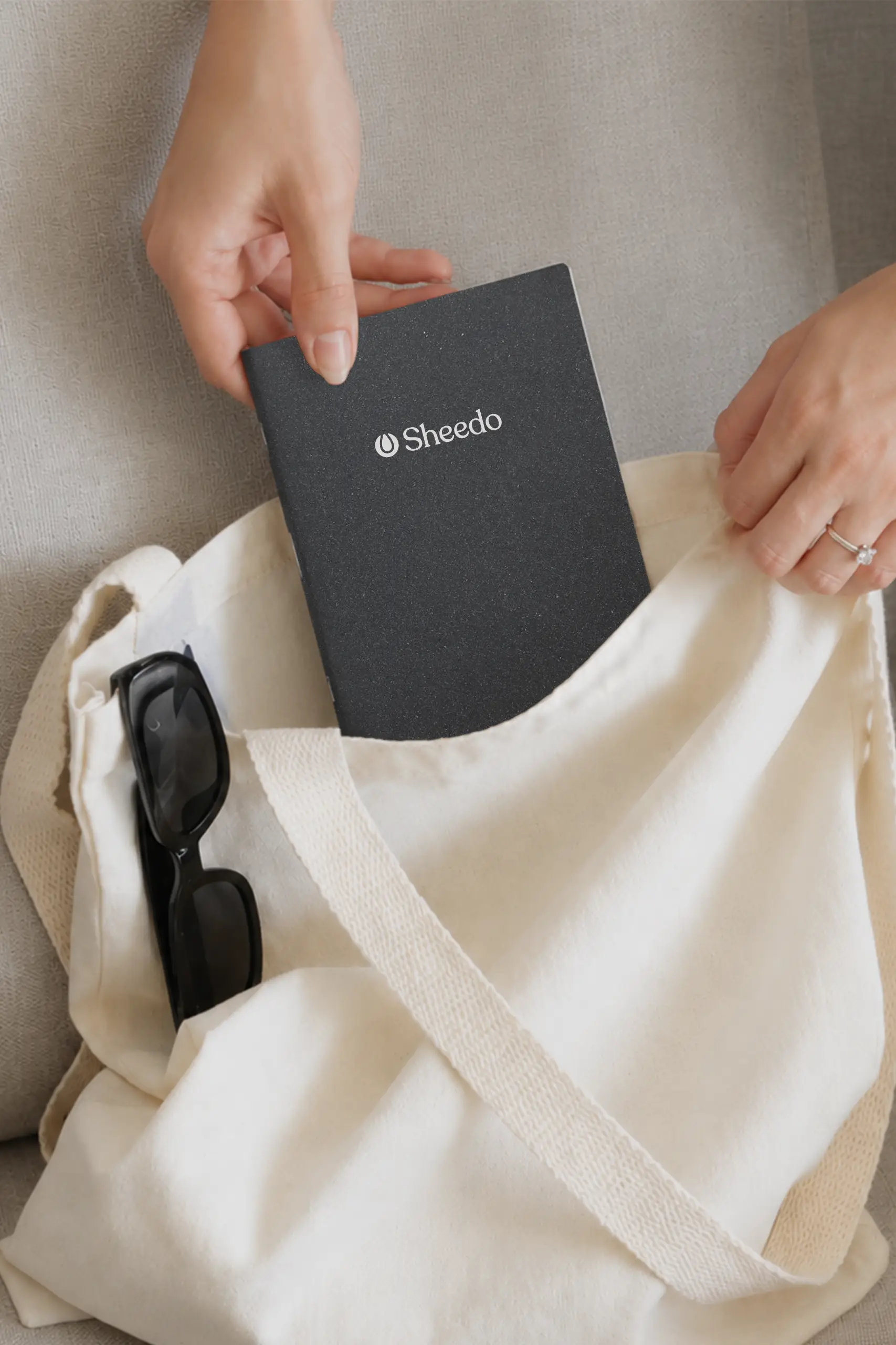 Persona con el cuaderno de cuero negro personalizado a una tinta introduciéndolo en una tote bag.