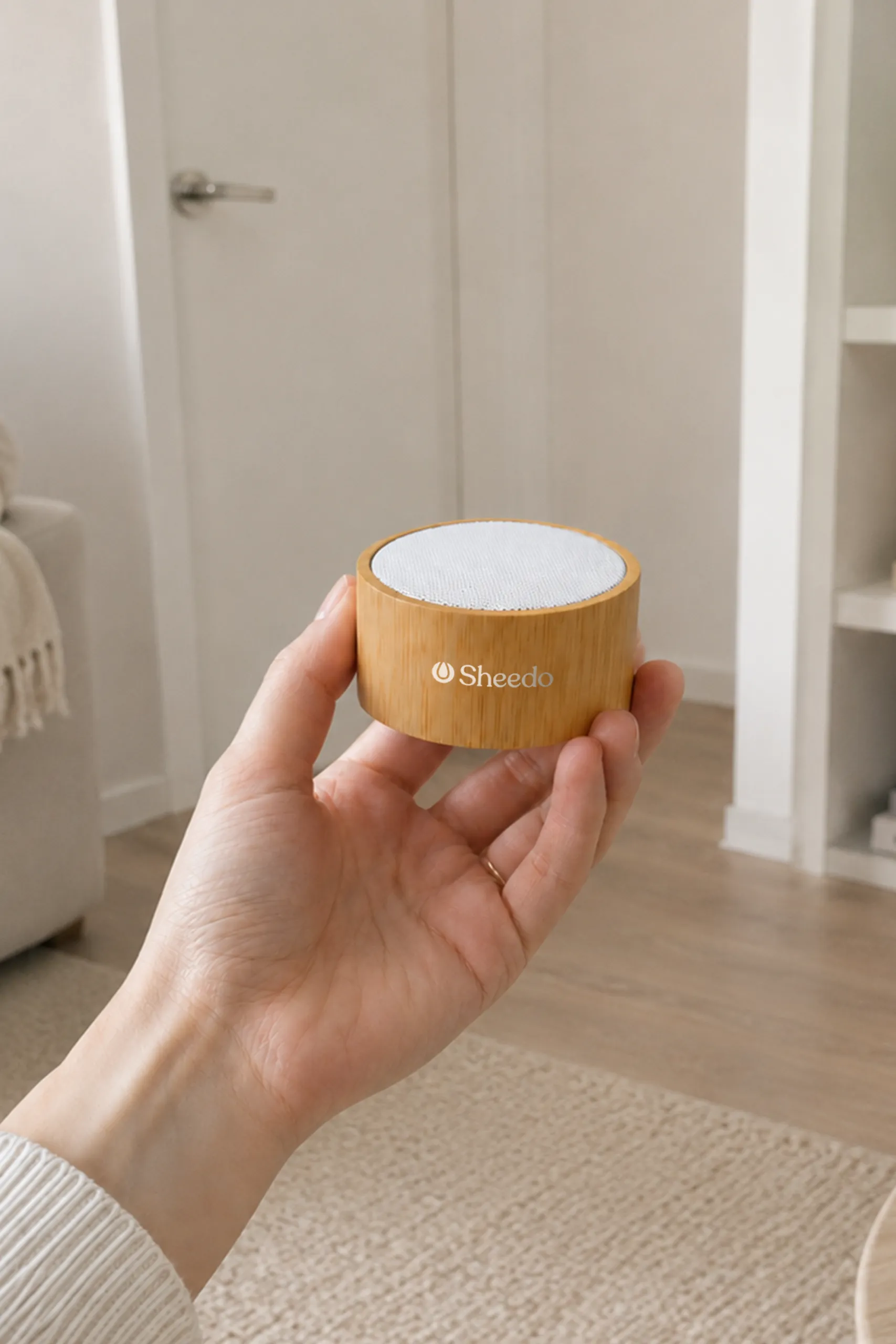 Altavoz con cuerpo de bambú en blanco con diseño personalizado a una tinta de LOGO. Sujeto por una persona en una habitación.