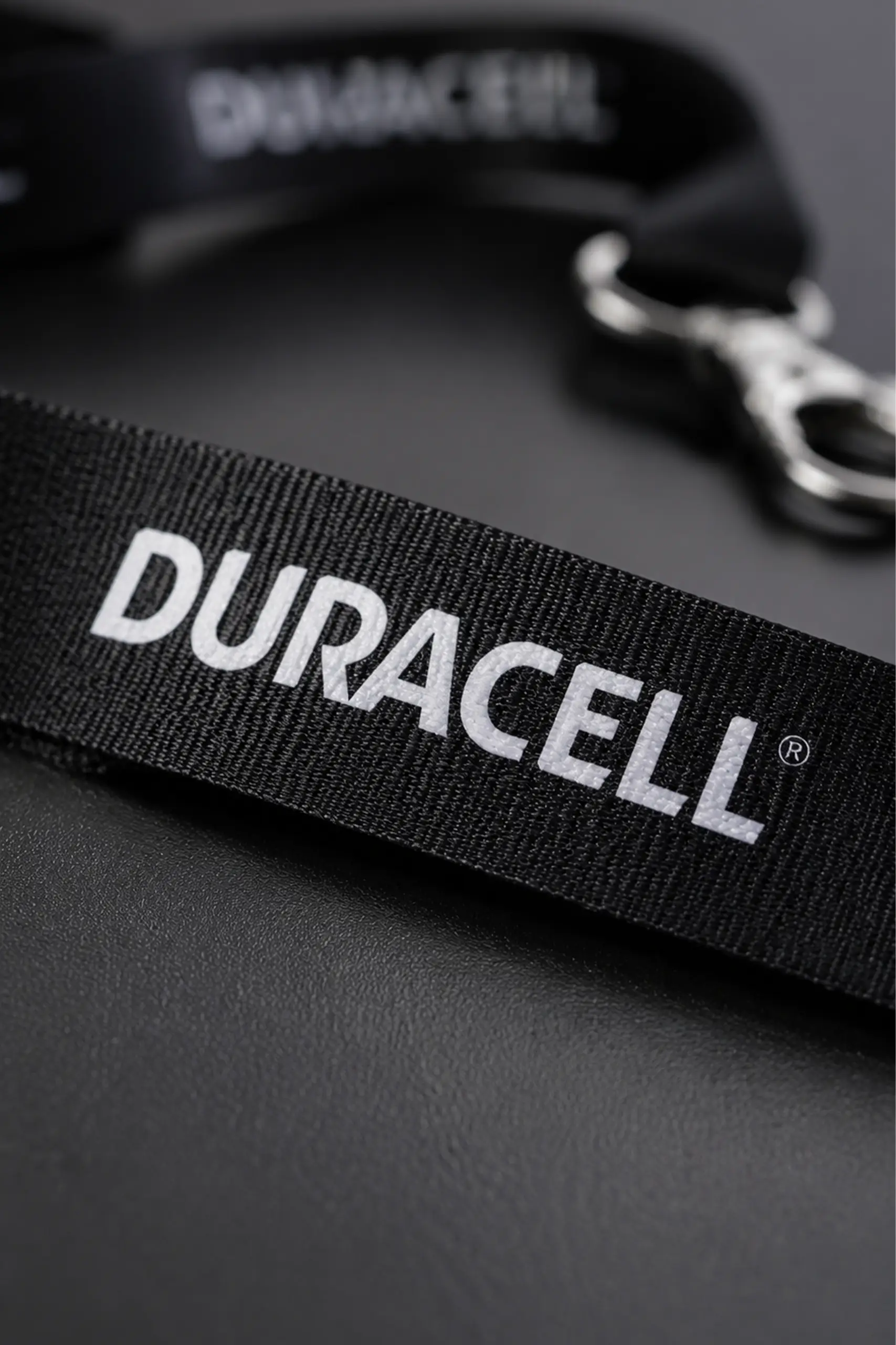 Lanyard de rpet de color negro personalizado con el logo de la marca Duracell, sobre una mesa negra