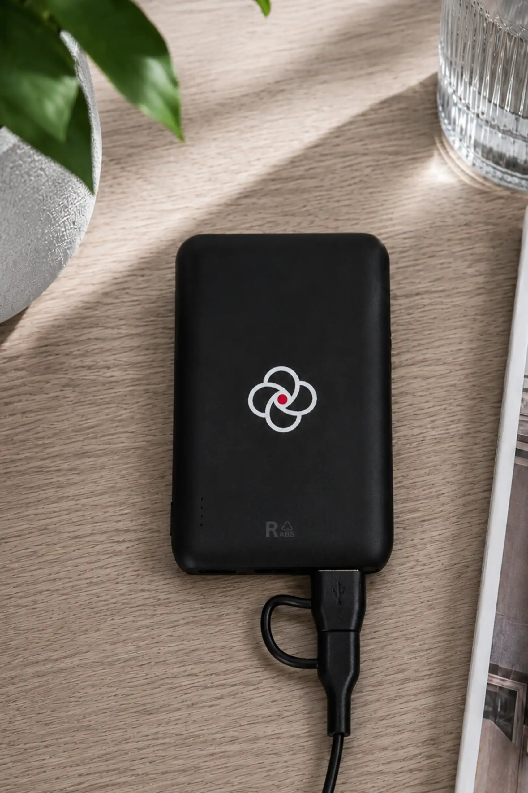 Power bank negro sobre una mesa de madera personalizado con el logo de la empresa MCI