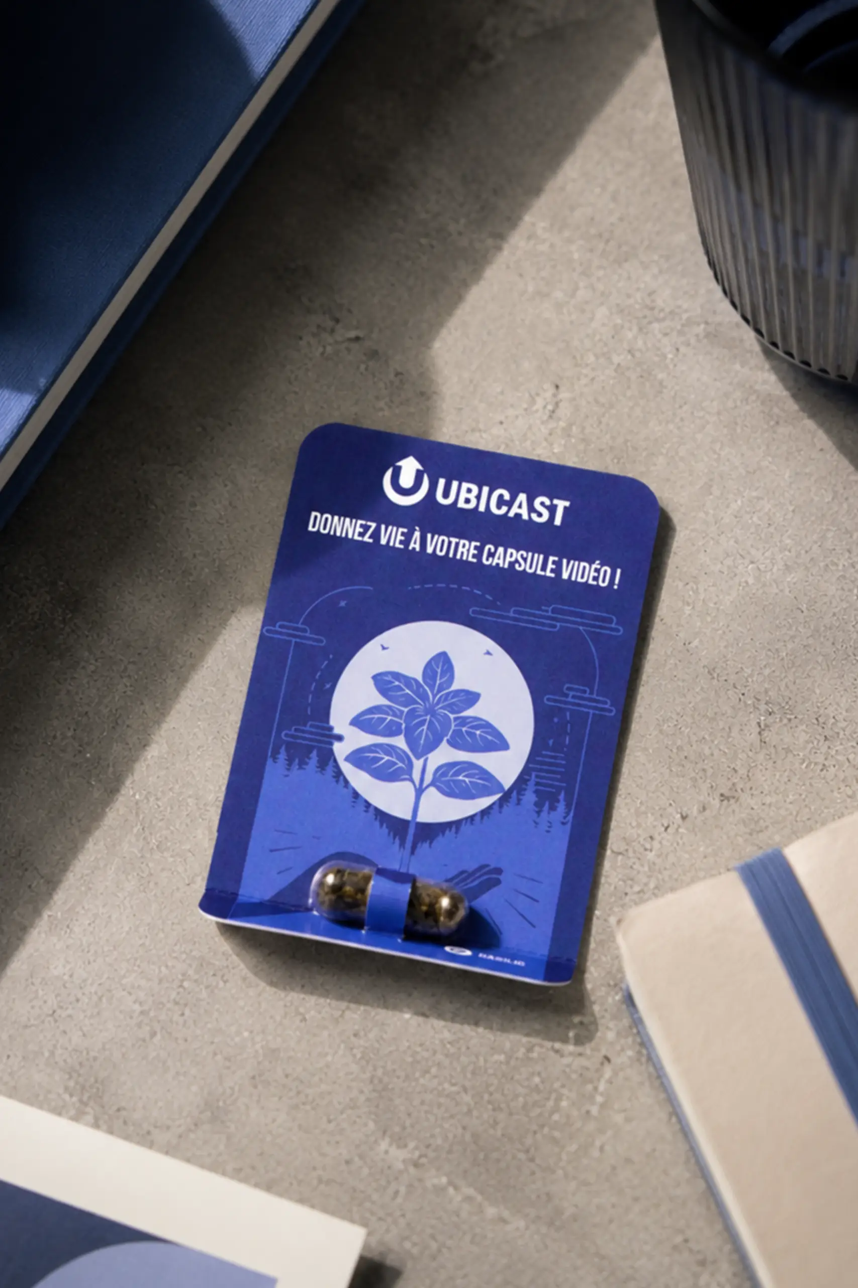 Cápsula de semillas personalizada con diseño corporativo de Ubicast, presentada sobre una tarjeta impresa personalizada para regalos de empresa sostenibles.