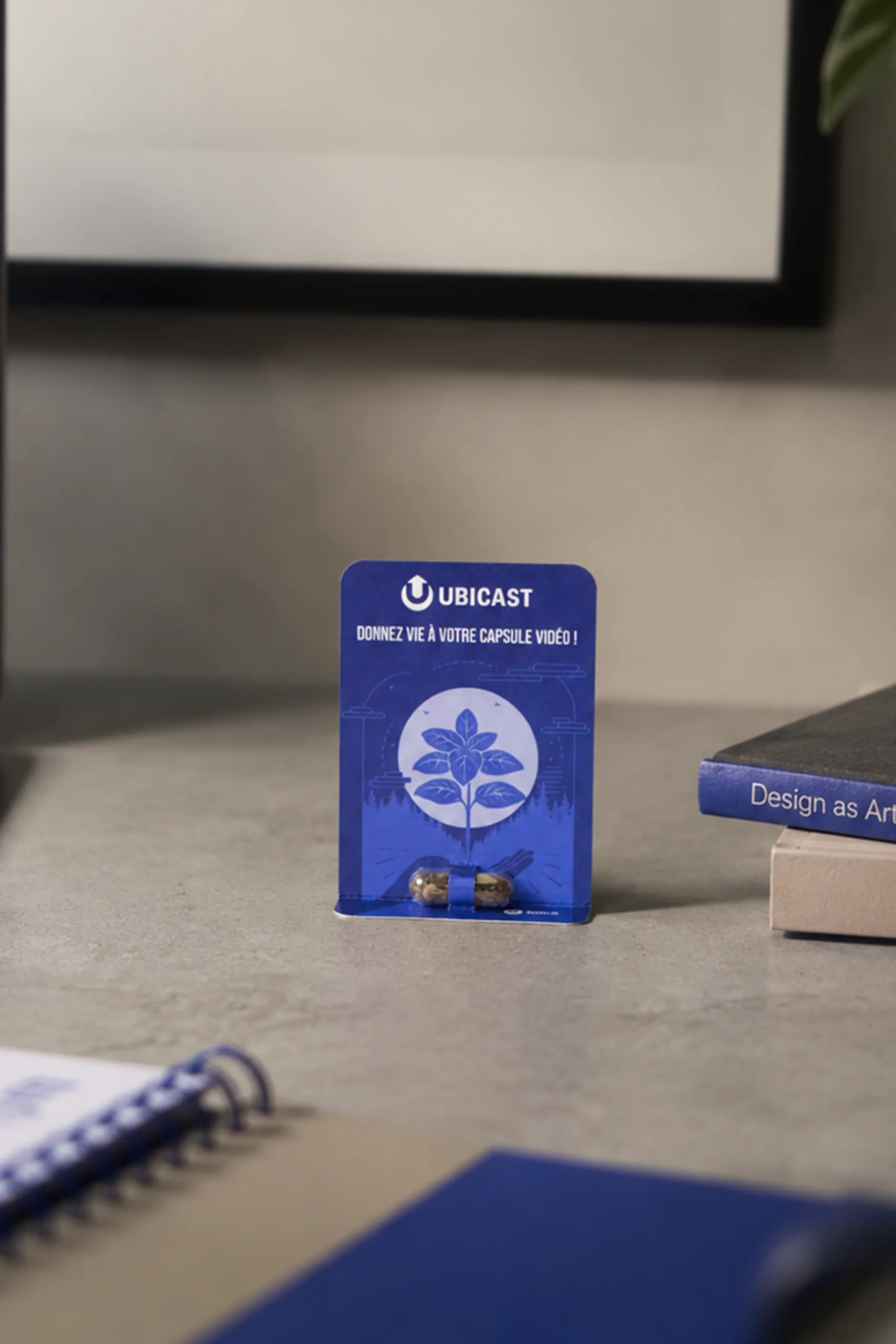 Cápsula de semillas personalizada con diseño corporativo de Ubicast, presentada sobre una tarjeta impresa personalizada para regalos de empresa sostenibles.