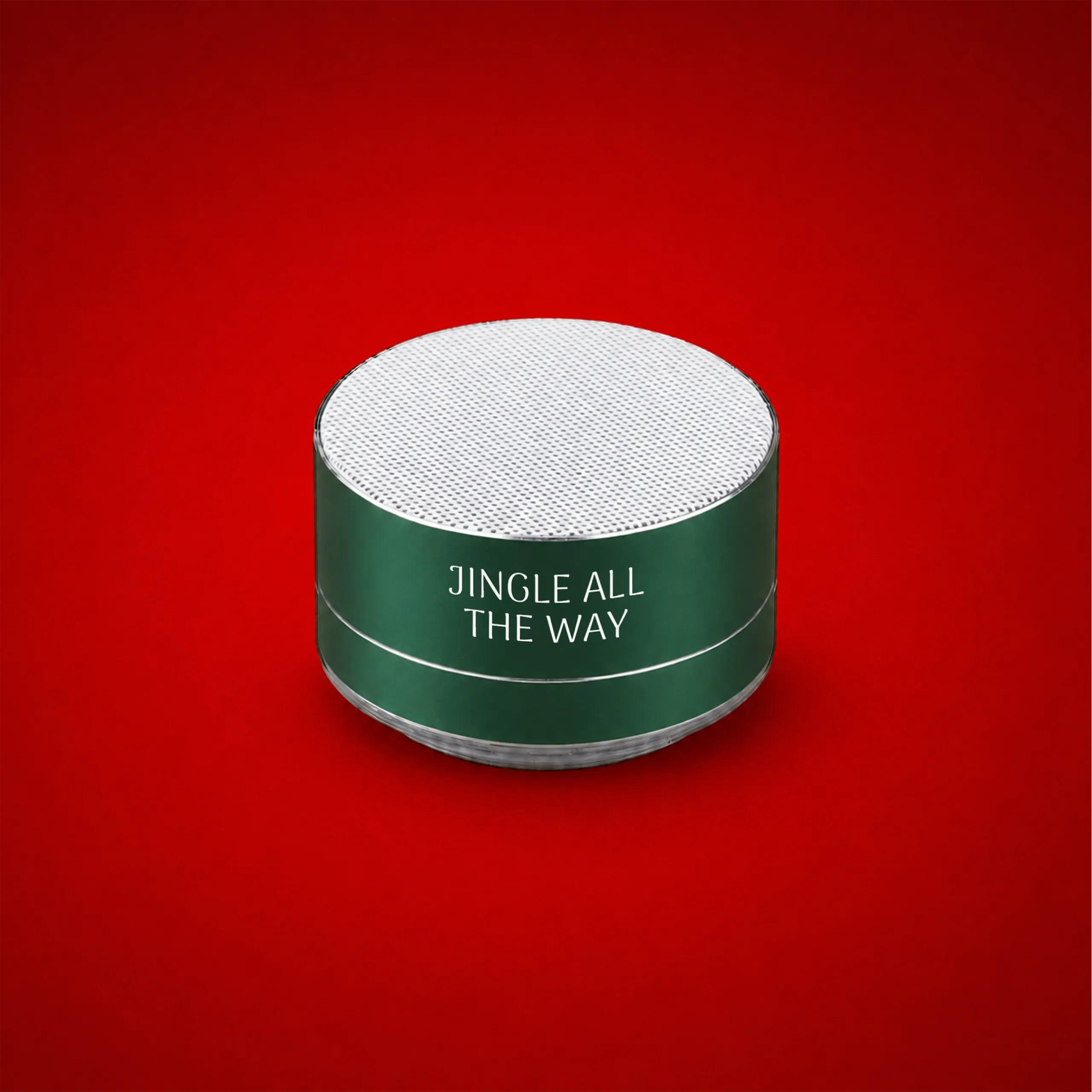 Altavoz de aluminio reciclado personalizado_XILO Altavoz de aluminio reciclado personalizado en verde con rejilla superior blanca y el texto "Jingle all the way", sobre fondo rojo.