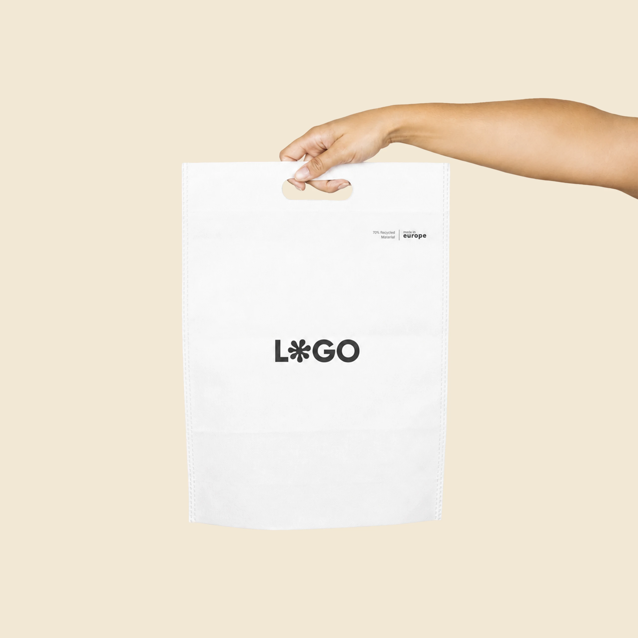 Bolsa en non woven reciclado 70g_m2 AIR Mano sosteniendo una bolsa blanca en non woven reciclado con asa troquelada y logo personalizado, mostrando su tamaño real.