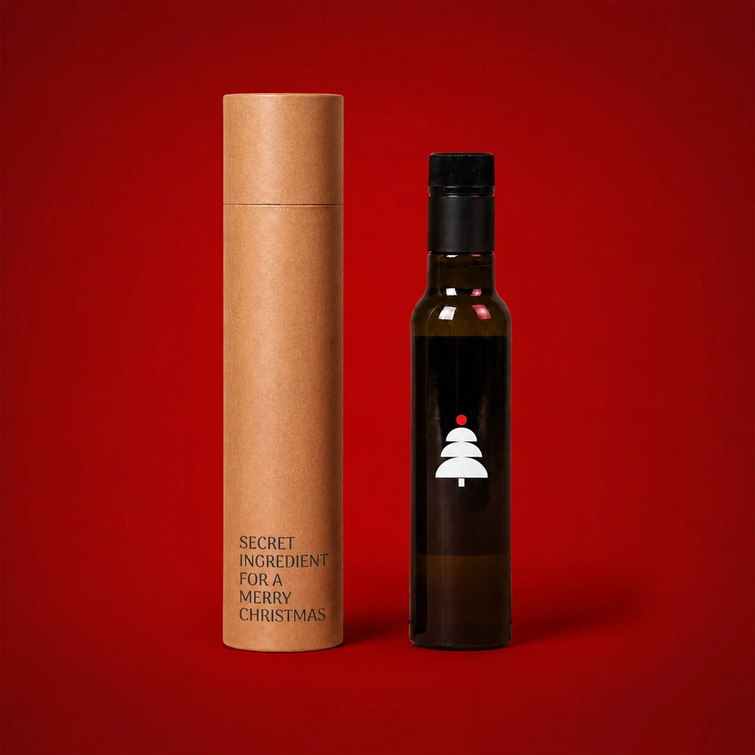 Botellas de aceite personalizadas_OLI Botella de aceite personalizada con etiqueta de árbol de Navidad en blanco, junto a su estuche cilíndrico de cartón kraft con el texto "Secret ingredient for a Merry Christmas", sobre fondo rojo.