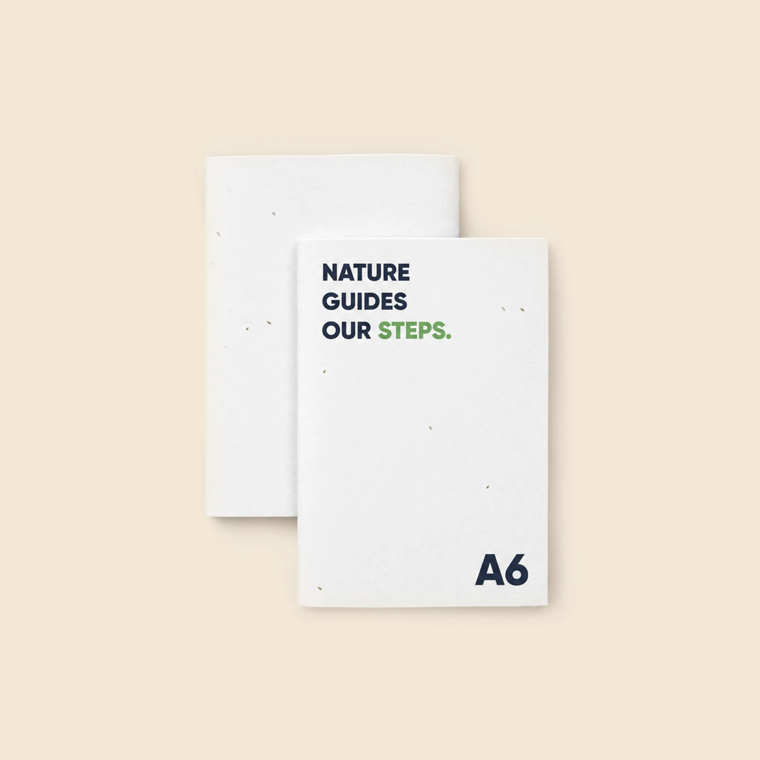 Two A6 notebooks with plantable seeded paper cover, one showing the front with the "Nature guides our steps" message and the other the back.