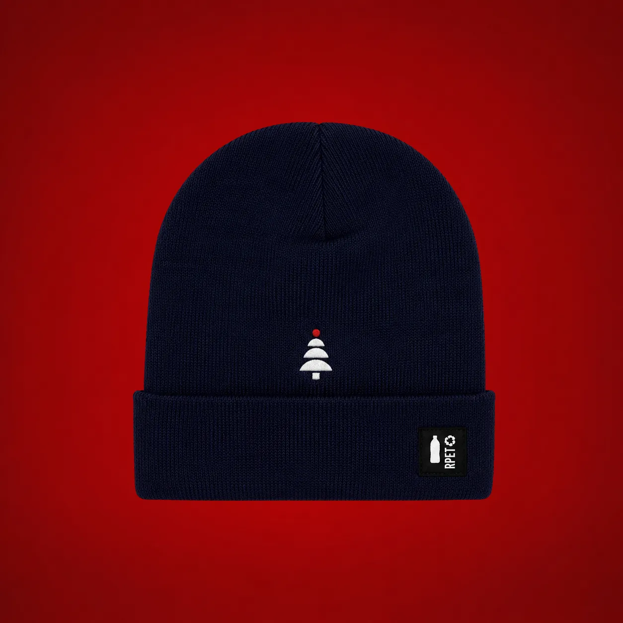 Gorro de invierno ecológico personalizado_TOGO Gorro de invierno ecológico en azul marino con un árbol de Navidad bordado en blanco y una bola roja, y una etiqueta textil con el icono de una botella y el texto "RPET", sobre fondo rojo.