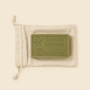 Jabón de Marsella con aceite de oliva bio sobre bolsa de algodón personalizable, fabricado en Francia, fondo beige.