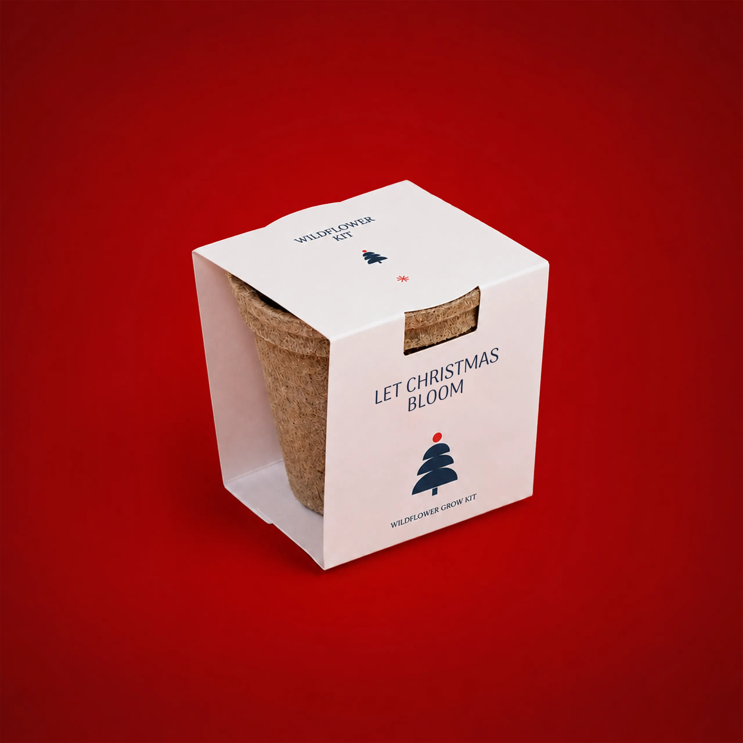 Kit plantable de fibra de coco_COCOON Kit plantable de fibra de coco en formato de maceta, presentado en su caja blanca con el texto "Wildflower Kit" y "Let Christmas Bloom, Wildflower Grow Kit", junto a un árbol de Navidad ilustrado, sobre fondo rojo.