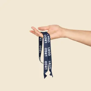 Mano sosteniendo un lanyard azul marino de rPET personalizado con logo, con terminación en pico, sobre fondo beige.