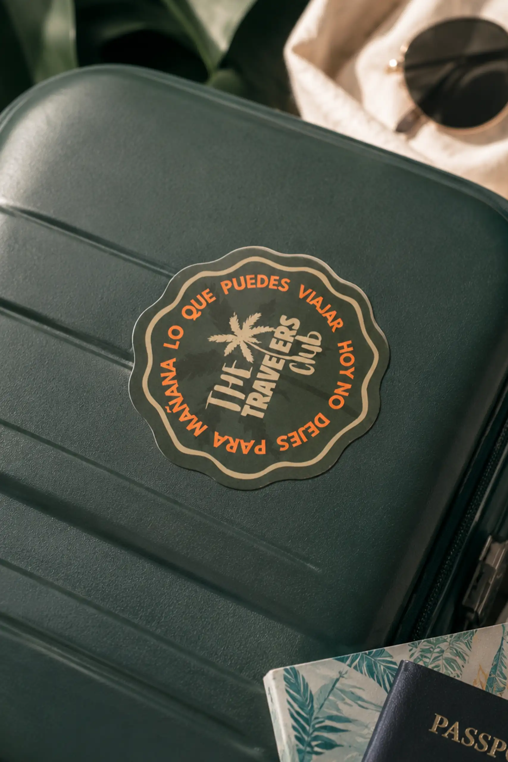 Pegatina troquelada de color verde personalizada con la imagen de la marca "The Trevelers Club", pegada sobre una maleta de viaje verde