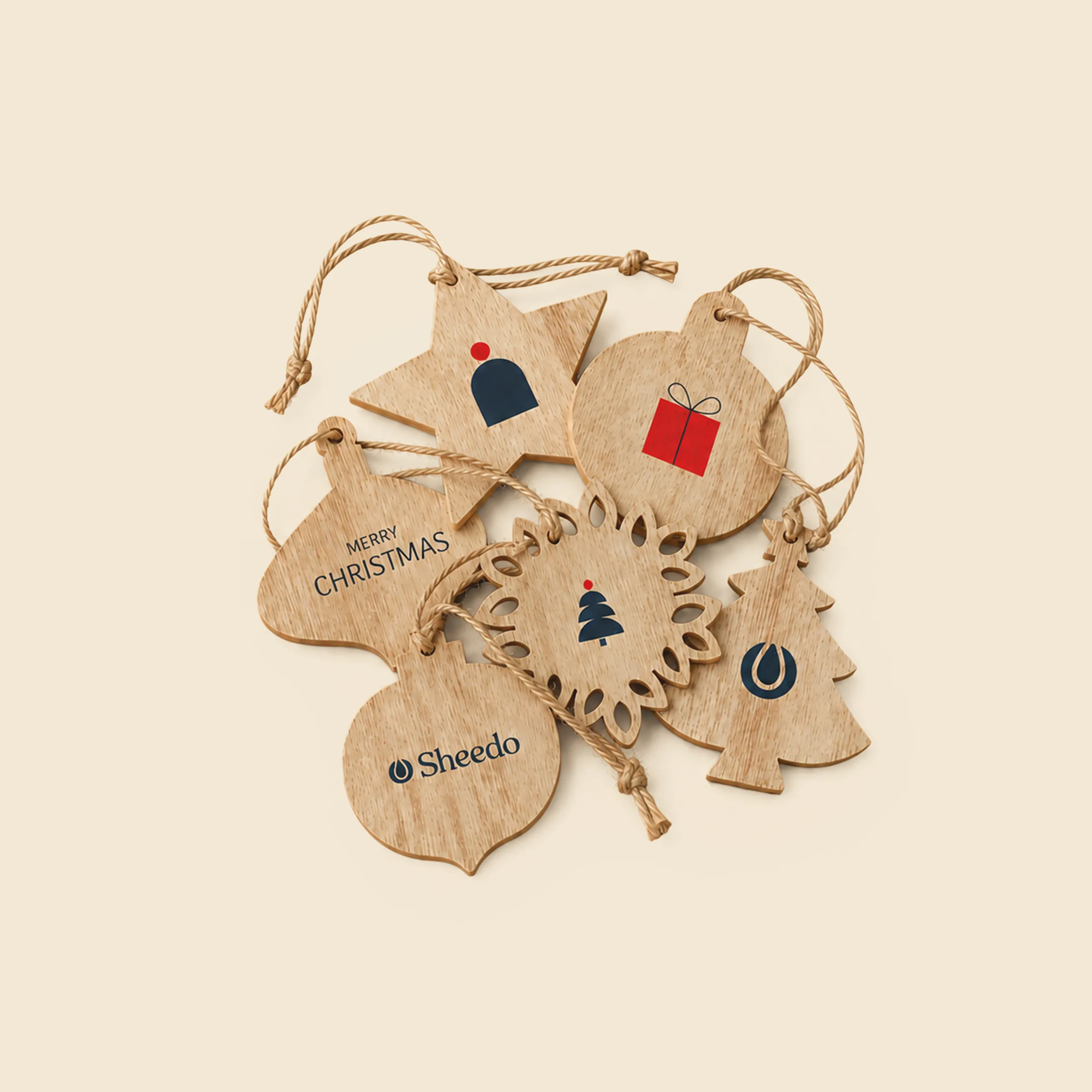 Set of seven personalised wooden Christmas ornaments in star, bauble, tree and snowflake shapes, with gold cord, decorated with gift, hat and tree icons plus the "Sheedo" logo and the "Merry Christmas" message.