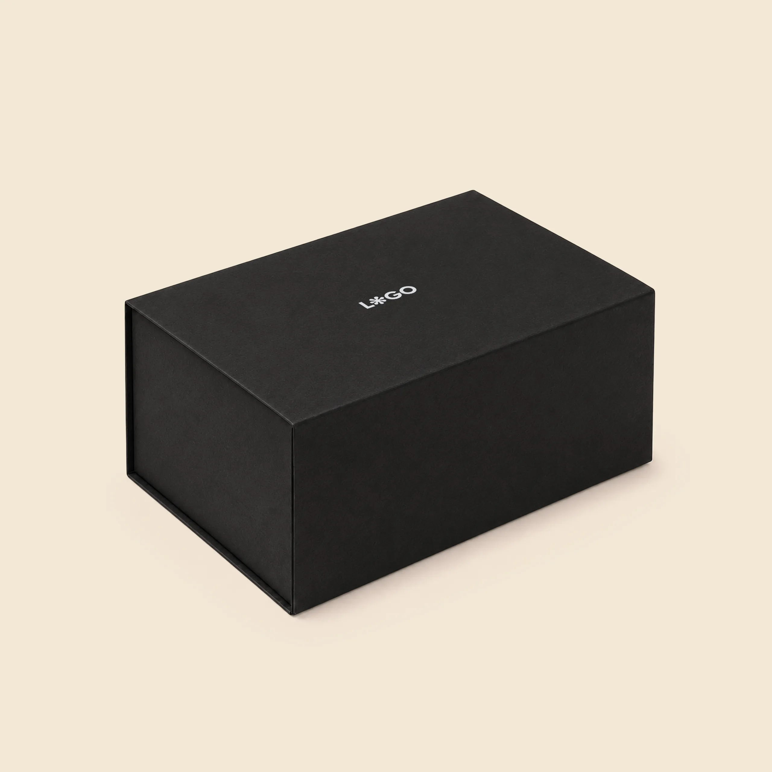Boîte cadeau noire à fermeture magnétique, vue en angle sur fond beige, avec le logo « L*GO » imprimé sur le couvercle.