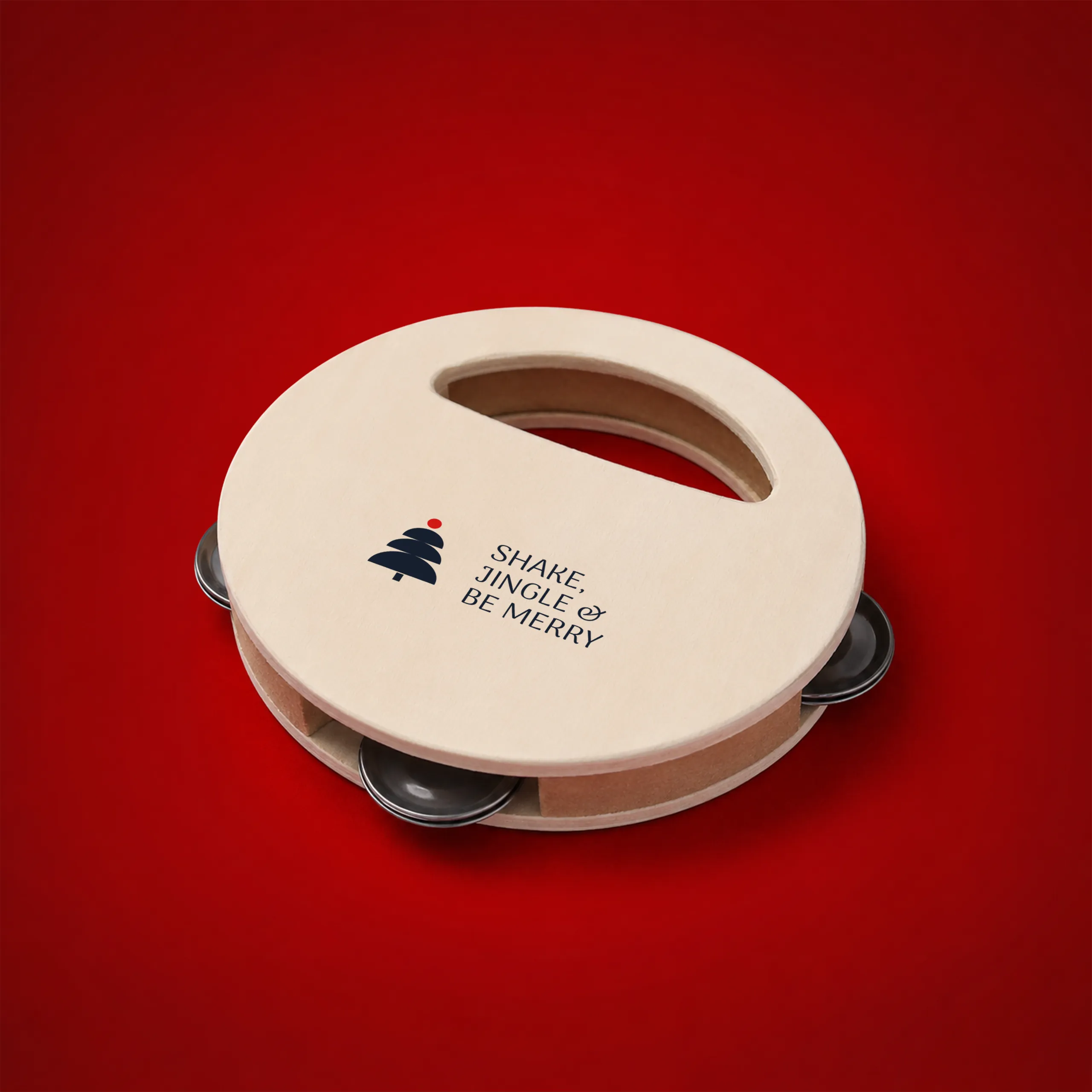 Personalised wooden tambourine on a festive red background, with a Christmas tree icon and the "Shake, jingle & be merry" message engraved on the surface.