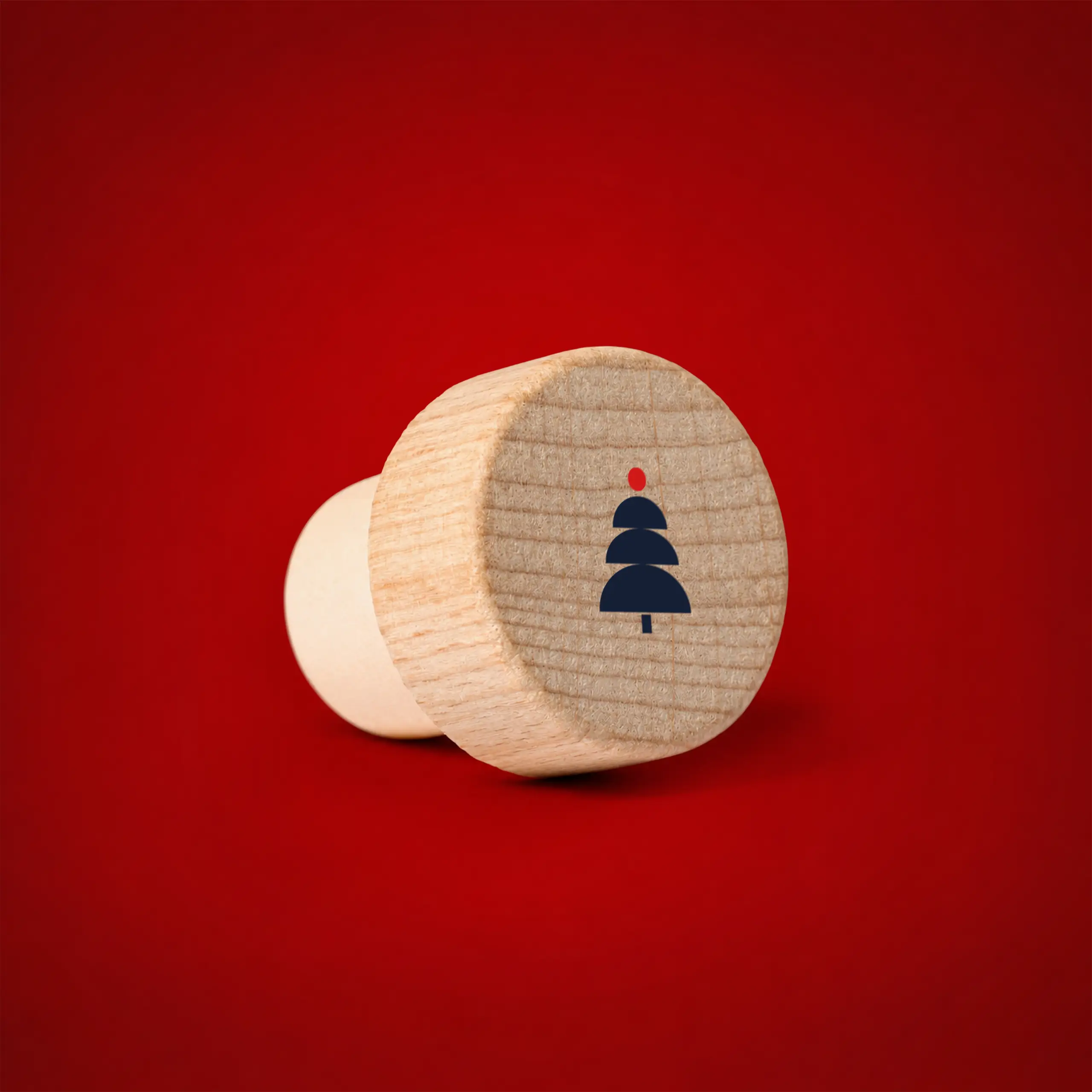 Reusable wooden bottle stopper on a festive red background, with a Christmas tree icon engraved on top.
