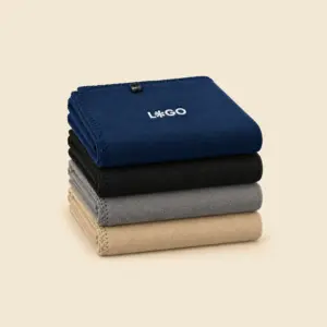 Cuatro mantas bordadas personalizables dobladas y apiladas en azul marino, negro, gris y beige, con remate de punto festón